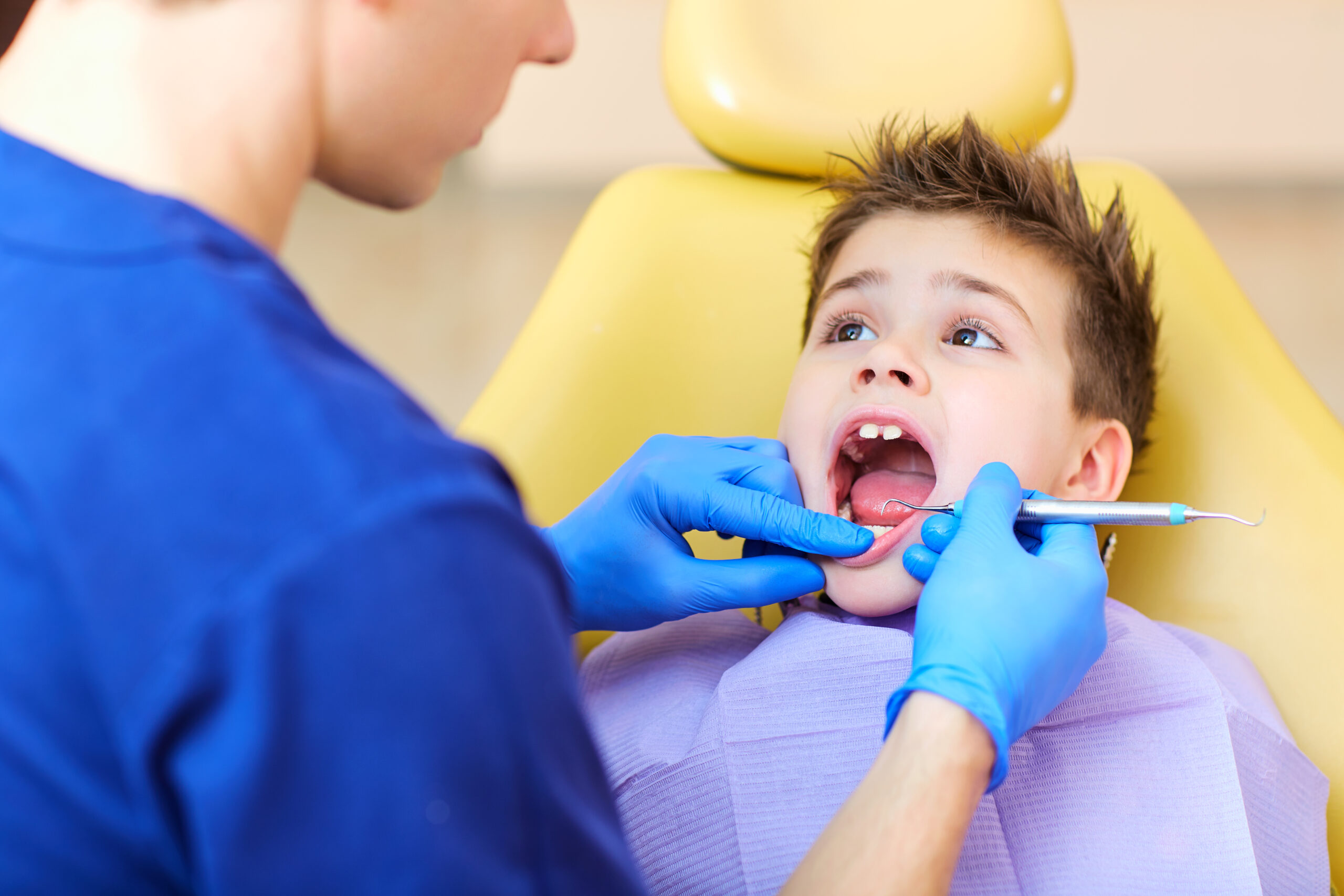 The dentist checking the teeth of boy teenager.