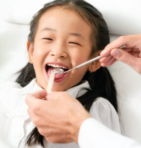 Friendly young dentist examining happy child teeth in dental clinic. Dentistry concept.