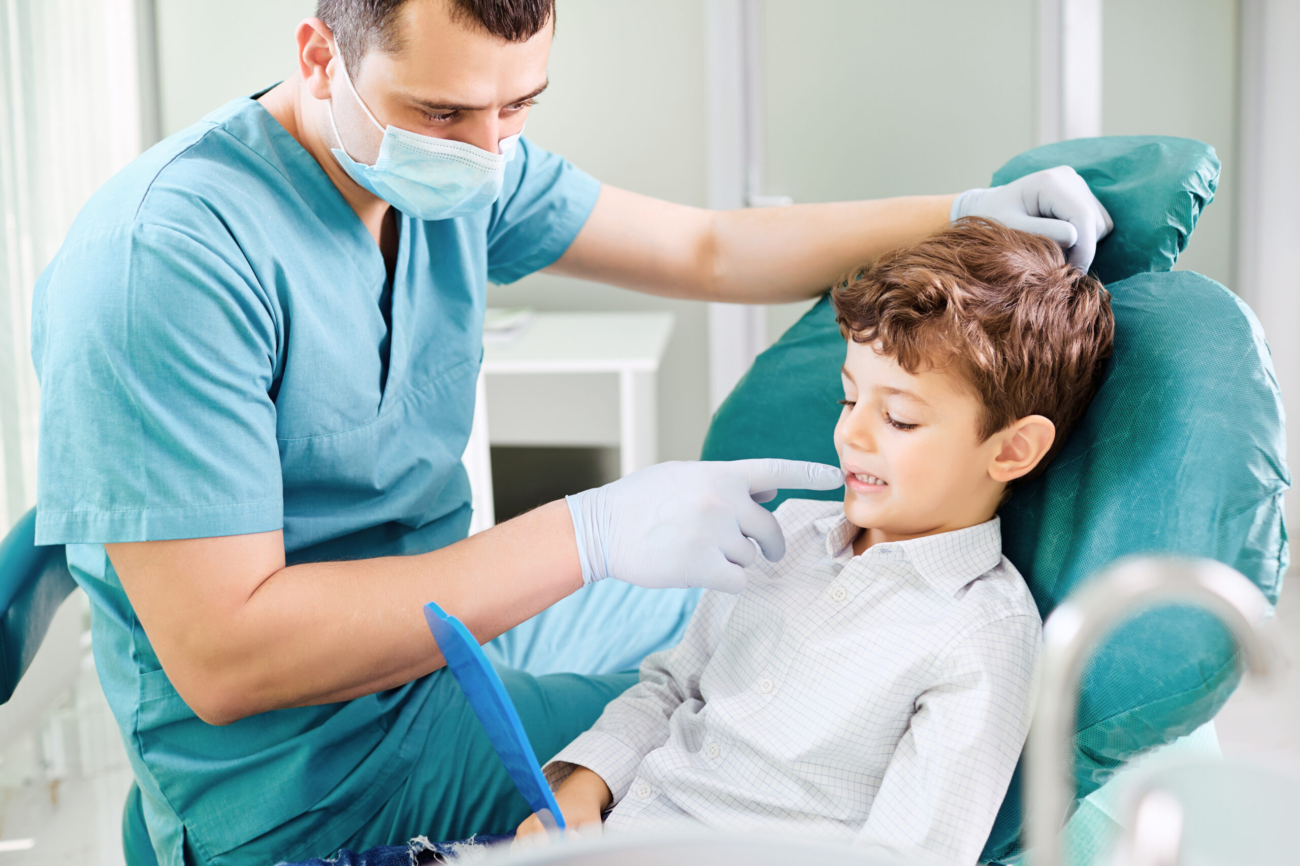 Young boy checking his teeth in a mirror with his pediatric dentist