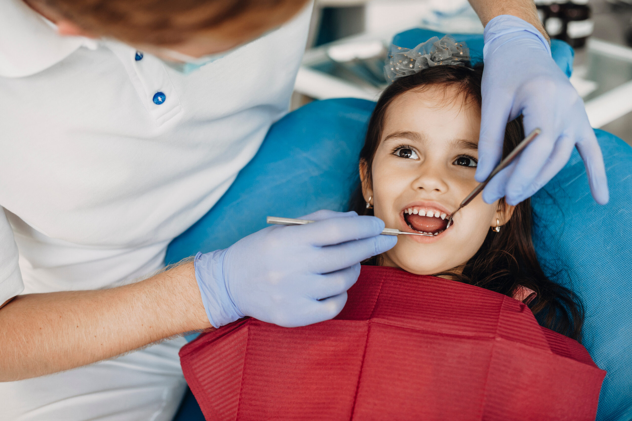 Pediatric dentist treating a young child's teeth in the dental chair