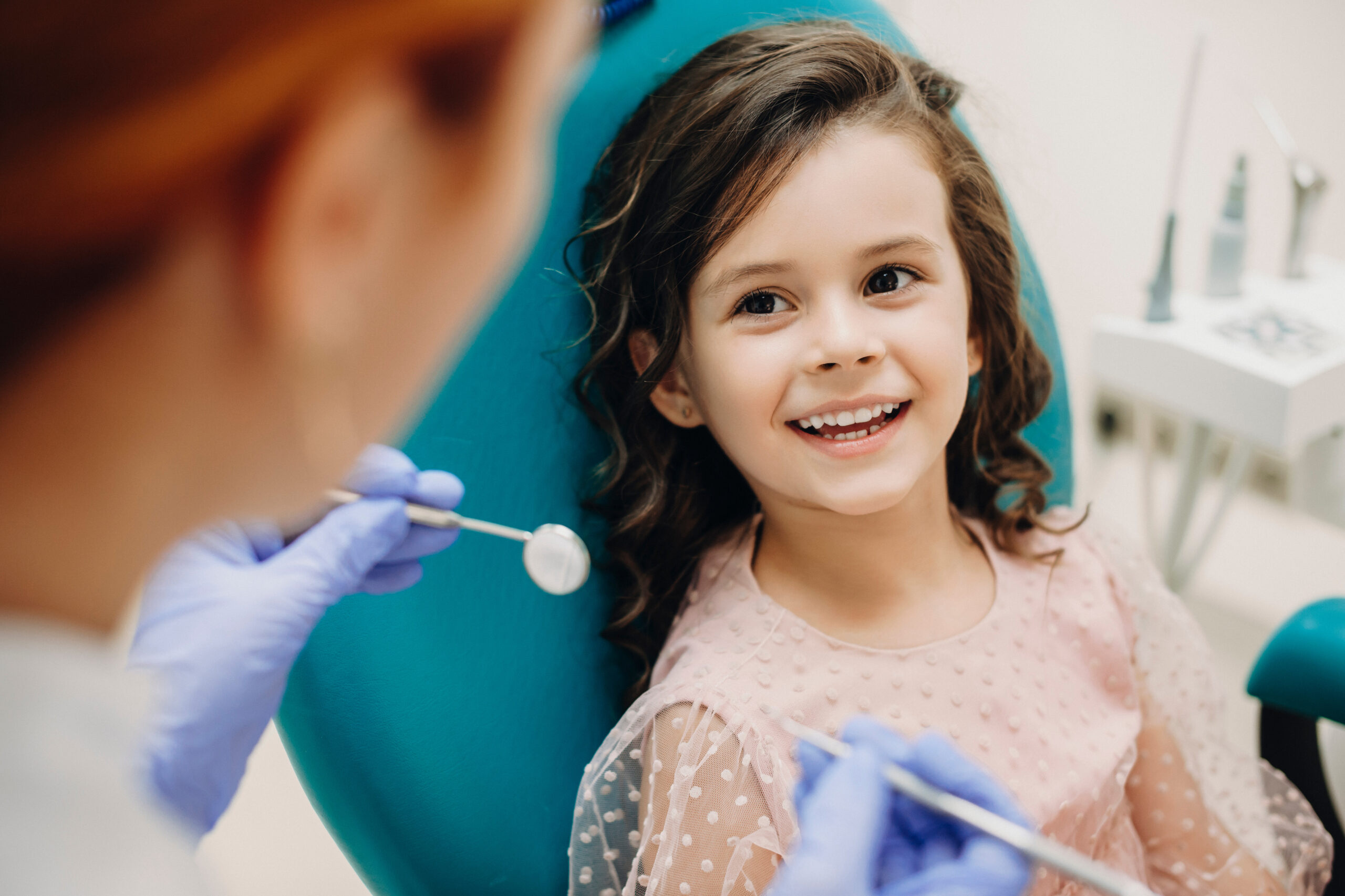 Lovely little kid smiling while talking with the pediatric dentist after a dental exam