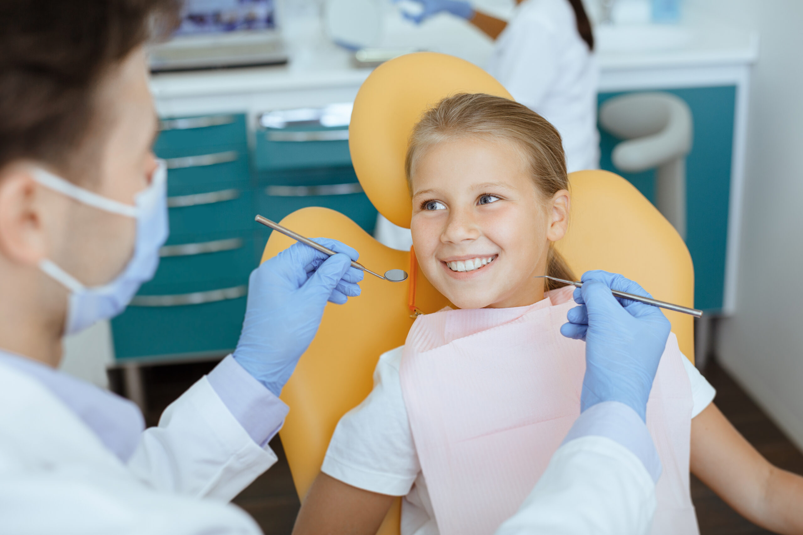 Pediatric dentist examining a child's teeth during a routine dental exam