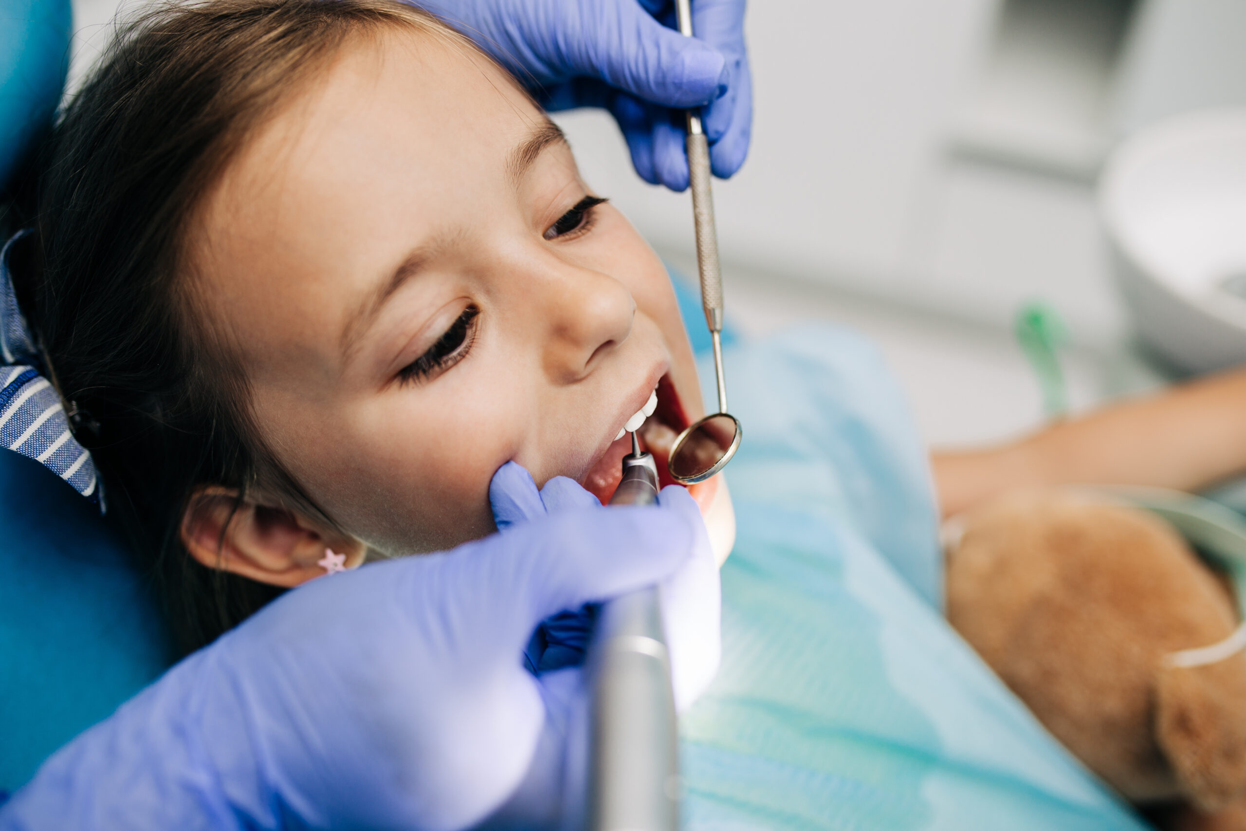 Child receiving pulp therapy treatment in a pediatric dental chair